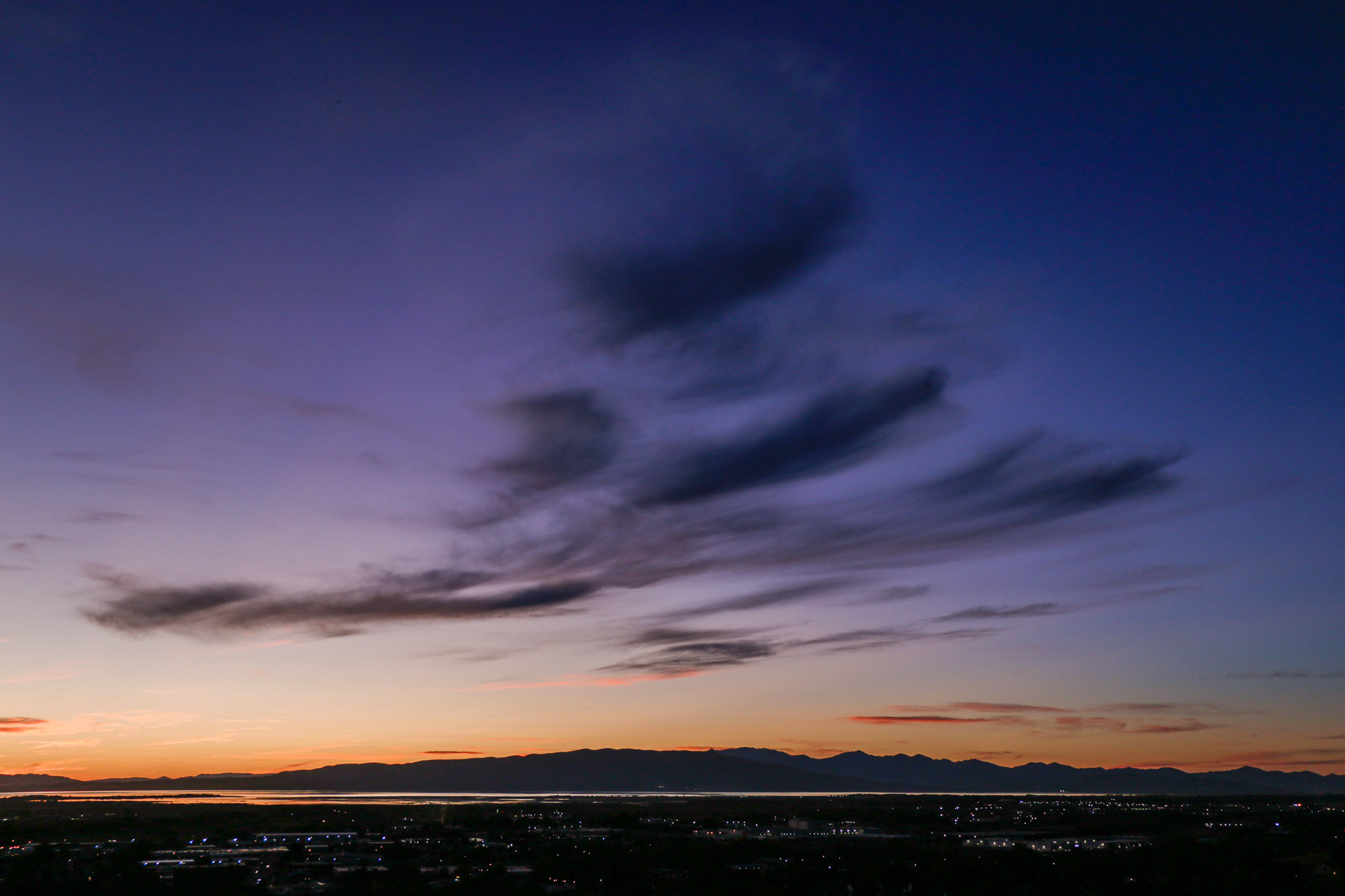 dark gray clouds form a kind of triangle at dusk above a town